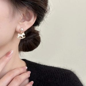 Elegant gold plated horse earrings with pearls and zircon shown on a fashion model