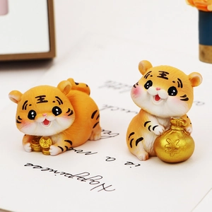 Close-up of two cute orange resin tiger figurines holding gold coins and money bags