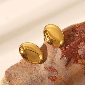 Boucles d'oreilles ovales dorées polies présentées sur une surface en pierre texturée