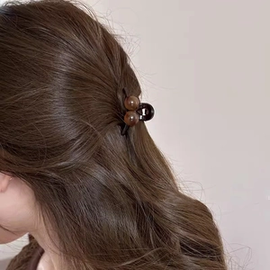 Amber cherry hair claw clip holding dark brown curly hair in an elegant updo