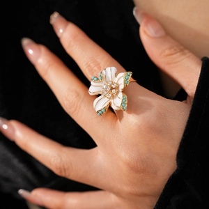 Gros plan d'une bague fleur en émail blanc avec perles turquoise et petits strass