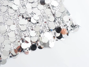Macro detail of shimmering silver sequins on white mesh for party dresses and accessories