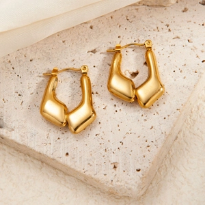 Detailed macro view of gold geometric star earrings with premium brushed steel texture