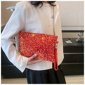 Close-up of a red sequin clutch bag with metallic clasp and red wrist strap for evening wear