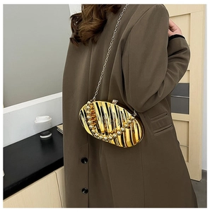 Detail of gold shell leaf clutch bag with vertical stripe pleats and beaded handle