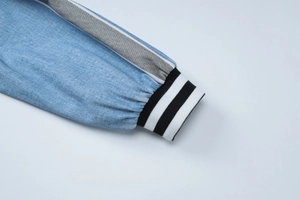 Detail view of blue denim texture with grey side tape and black-white ribbed cuffs