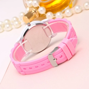 Pink silicone watch with white case displayed with pearls and gold perfume bottle