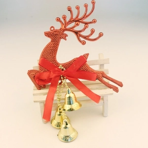 Copper reindeer Christmas ornament with red satin bow and three gold bells on wooden chair