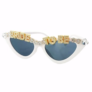Close-up of white cat eye sunglasses with rhinestone BRIDE TO BE lettering and pearls