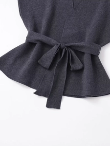 Dettaglio del gilet in maglia grigio scuro con cintura annodata e trama in tessuto premium