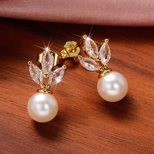 Elegant gold earrings with marquise-cut stones and white pearls on pink silk fabric