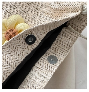 Close-up of metal magnetic buckle and herringbone woven texture on straw bucket bag