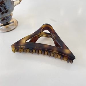 Detailed view of large triangular tortoiseshell hair claw with amber resin texture
