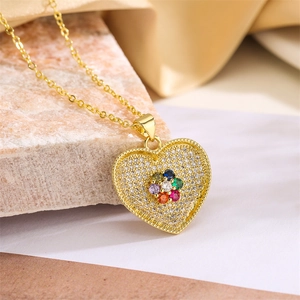 Macro detail of heart pendant with multi-color gems and pavé zircon on gold chain