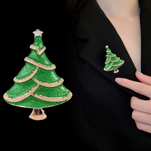 Green Christmas tree brooch with gold trim and sparkling glitter on a black background