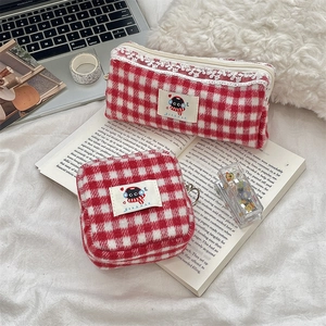 Detail of red checkered knit pencil case and square pouch with lace trim on a desk