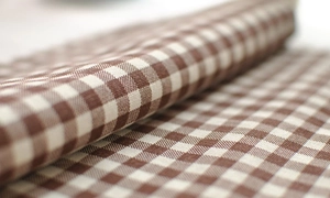 Detail of French linen cotton tea towel with brown and white gingham checkered pattern