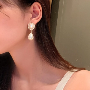 Macro shot of elegant gold pearl drop earrings with sparkling zircon crystals on model