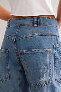 Vue macro détaillée des poches arrière et de la texture denim vieilli du jean bleu large