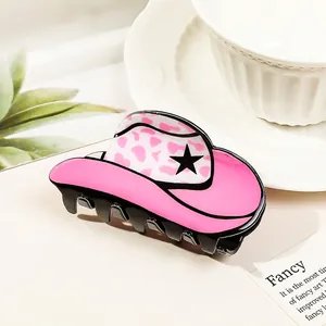 Pink cow print cowboy hat hair claw clip with star detail on a decorative plate