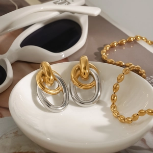 Vue détaillée de boucles d'oreilles ovales entrelacées or et argent sur un plateau