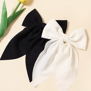 Detail of white and black bow hair clips with long ribbons and fine striped texture