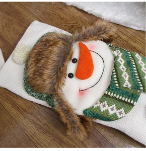 Detailed view of a white knitted Christmas stocking featuring a plush snowman with green scarf