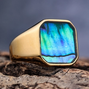 Macro view of gold square signet ring with iridescent abalone shell inlay on bark