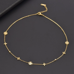 Collier en acier titane doré avec pendentifs trèfle, étoile et diamant sur fond noir