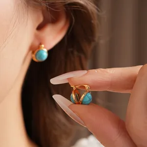 Boucles d'oreilles vintage dorées avec résine turquoise portées à l'oreille