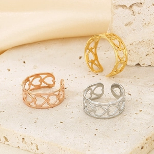 Detailed view of hollow heart rings in gold, silver, and rose gold on a stone base