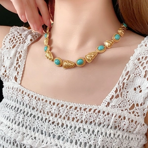 Gros plan d'un collier vintage doré avec pierres turquoises sur un mannequin en dentelle