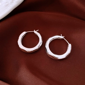 Macro shot of silver irregular ripple earrings on luxury dark brown velvet fabric