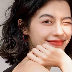 Close-up of red geometric hoop earring on model showing elegant matte paint finish
