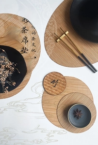 Detailed view of woven bamboo tea mats in various sizes with traditional ink wash background
