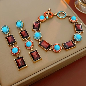 Vintage jewelry set with turquoise and red stones on a beige leather display box