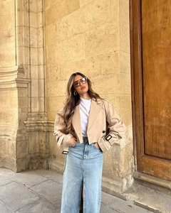 Dettaglio del trench corto color kaki con cinturini ai polsi e gonna lunga in denim