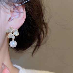 Close-up of elegant flower pearl earrings with sparkling zircons worn by a female model
