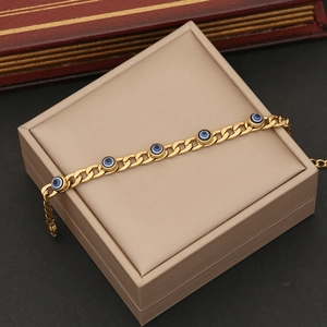 Detail of gold chain necklace with blue evil eye beads on a beige jewelry box