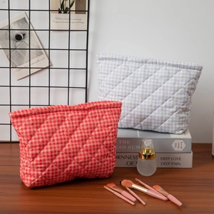 Quilted floral cosmetic bag in orange and blue plaid on a wooden desk setup