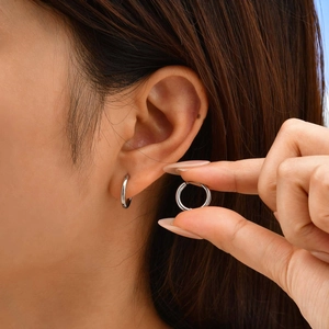 Close-up of minimalist silver stainless steel hoop earrings with polished mirror finish