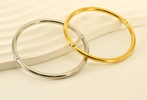Detailed view of polished gold and silver stainless steel bangles with secure clasps