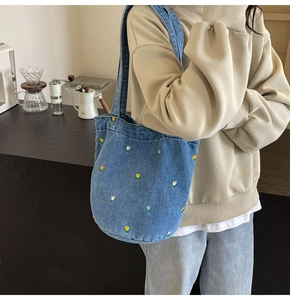 Vue détaillée du sac cabas en jean bleu avec broderies florales et poignées solides