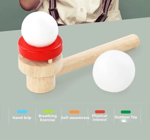 Flat lay of wooden lung capacity trainer with blowing pipe and two white foam balls