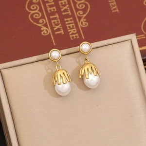 Close-up of golden lava fringe wrapped irregular pearl earrings on a luxury jewelry box