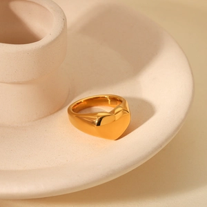 Detailed view of polished 18K gold plated heart ring on a ceramic tray