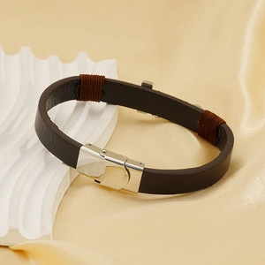 Bracciale in pelle marrone con chiusura in acciaio inossidabile su sfondo di seta