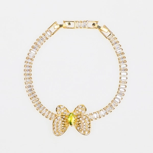 Detailed close-up of golden butterfly bracelet with white zircon and green marquise stone