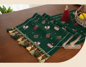 Detail of green Christmas table runner with jacquard Santa Claus and multi-color tassels