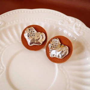 Close-up of irregular silver metal plate and brown velvet resin stud earrings